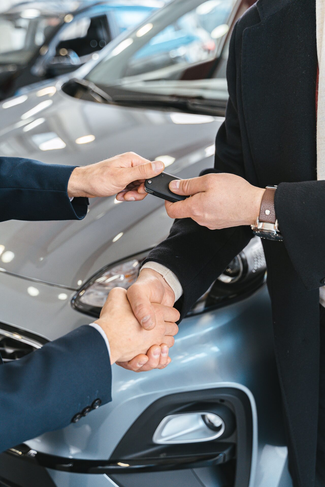 Vendedor entregando las llaves de un carro nuevo al comprador tras cerrar el financiamiento
