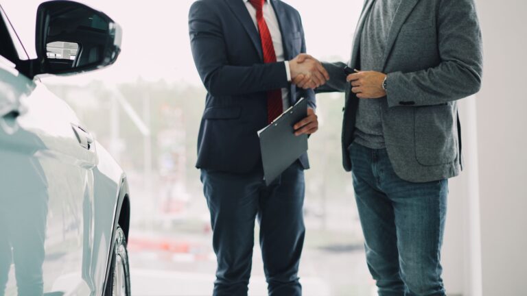 Comprador y vendedor cerrando el acuerdo de financiamiento de un carro en el showroom